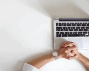 A person wearing a watch near a laptop