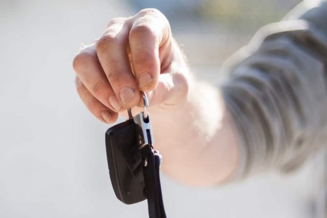 a person holding new car keys